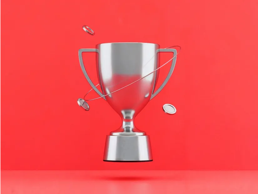 Серебряный трофей с парящими монетами на красном фоне, символизирующий Deriv Trading Tournaments