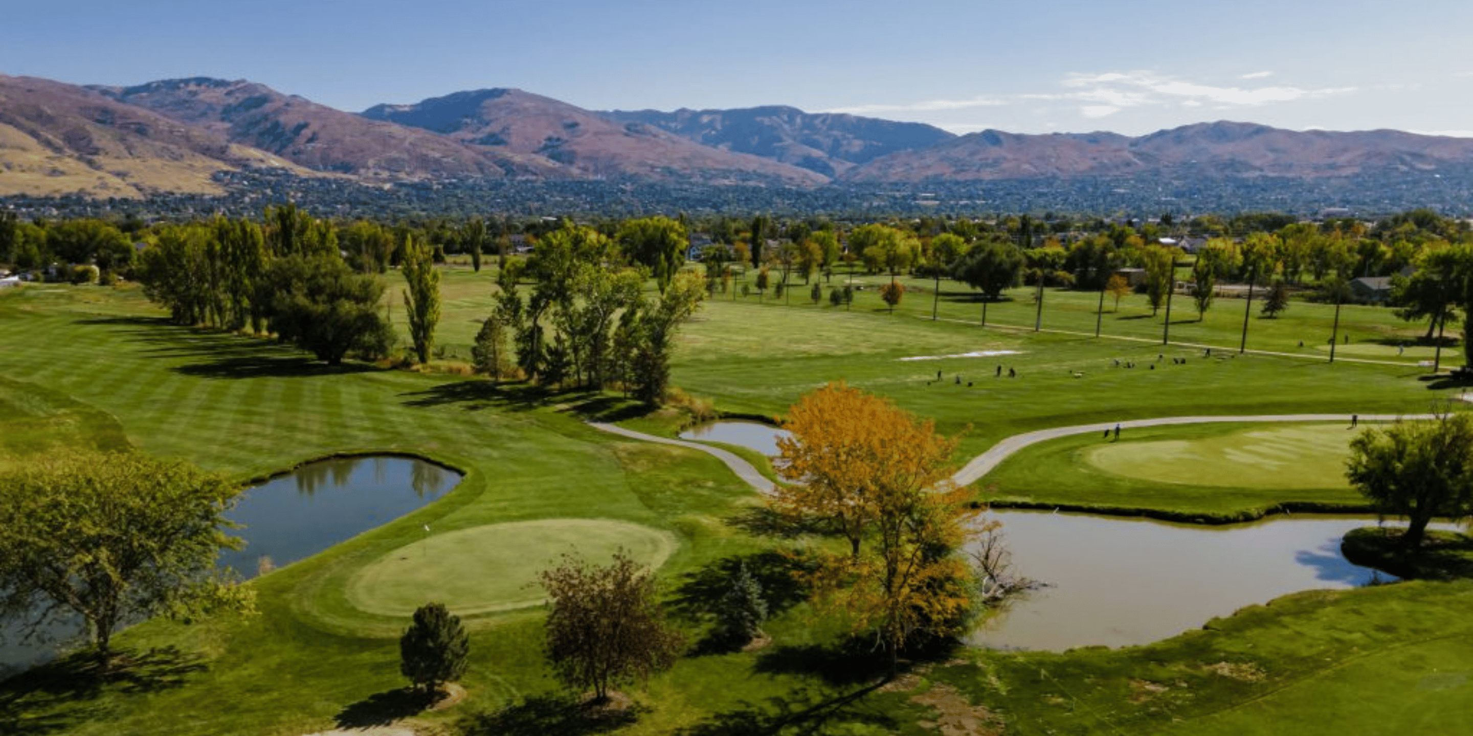 A scenic view of Lakeside Golf Course with lush greens and mountains rising in the background.