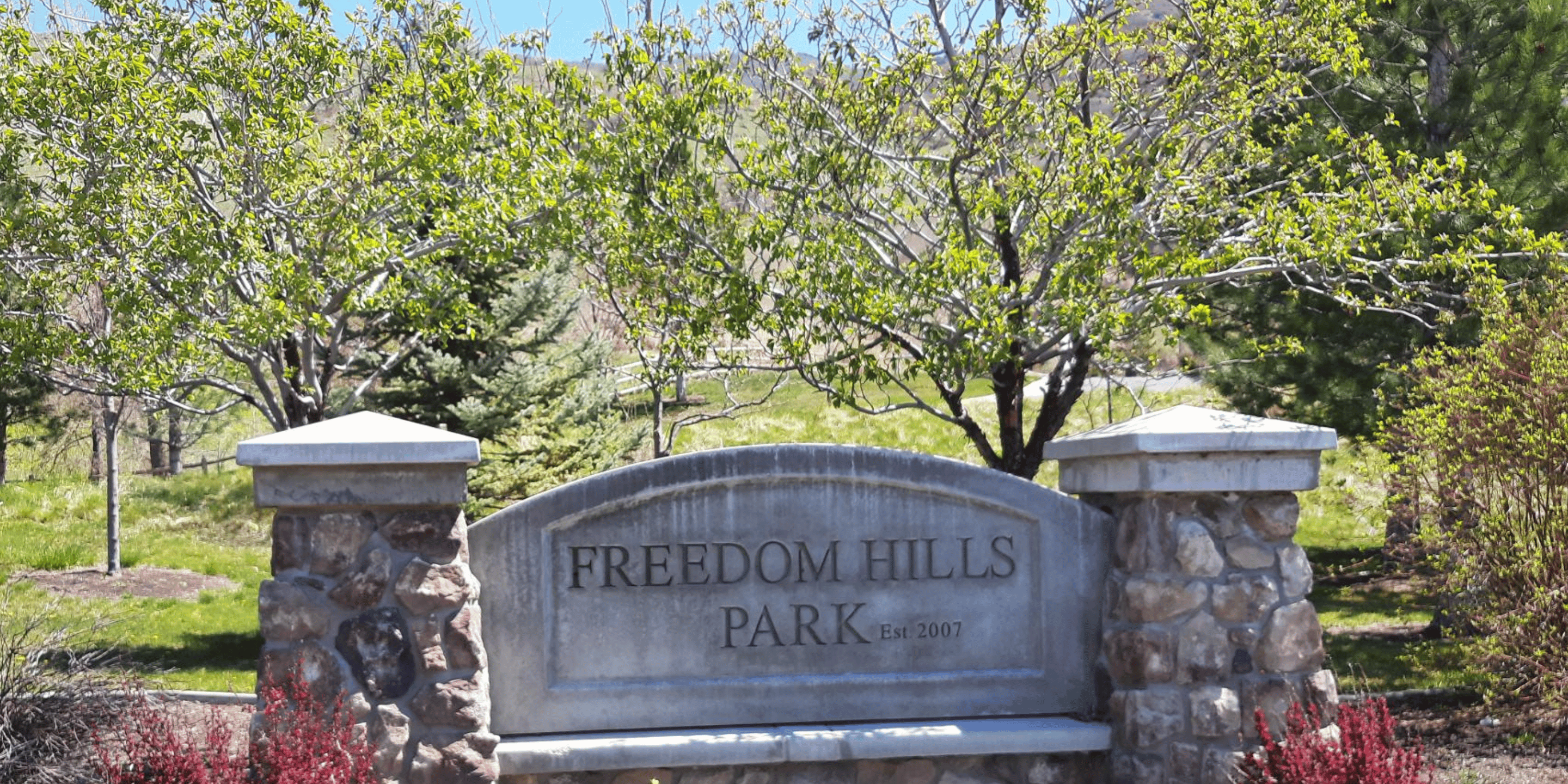 Sign for Freedom Hills Park displayed prominently within the park in Centerville, UT.