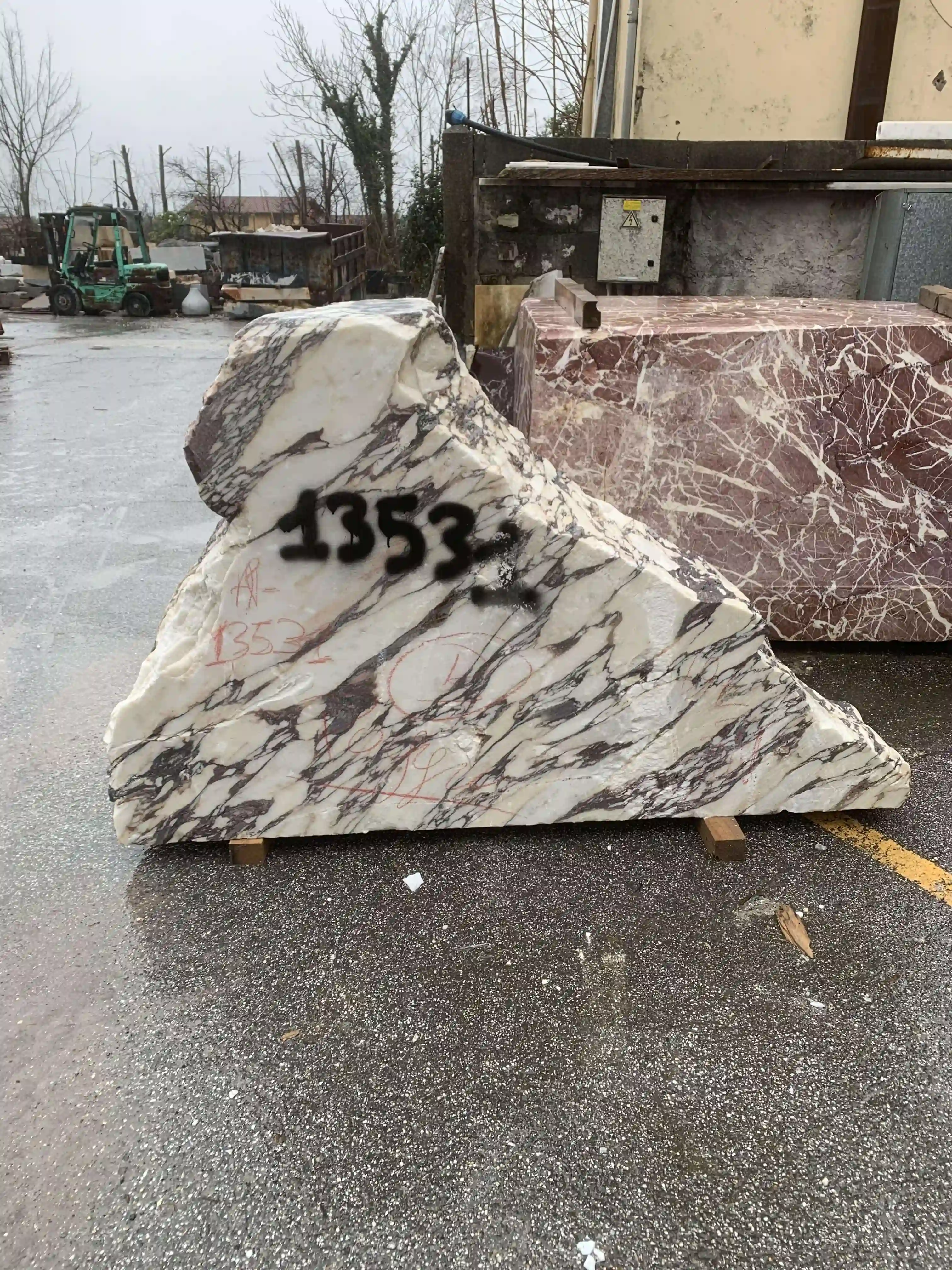 Large triangular slab of white marble with dark veins and black spray-painted numbers, placed outdoors on wooden supports.