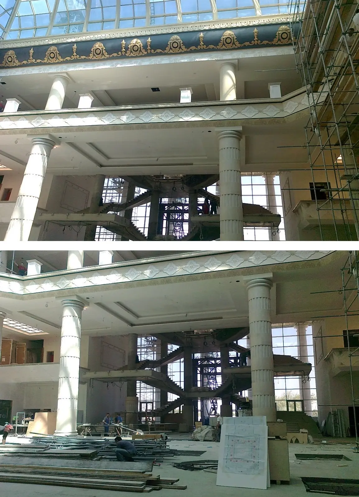 Interior of a large building under construction with white columns, scaffolding, and a central staircase.