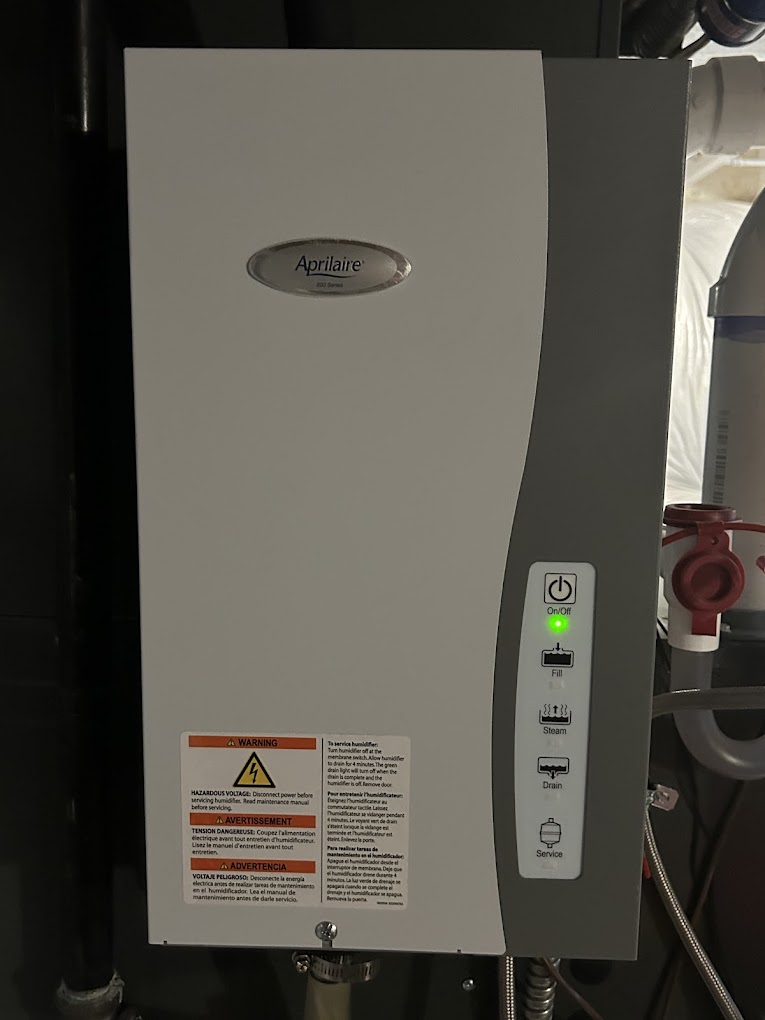 Tankless water heater installation with Aprilaire unit, featuring control panel and warning label, highlighting HVAC service for hot water efficiency.