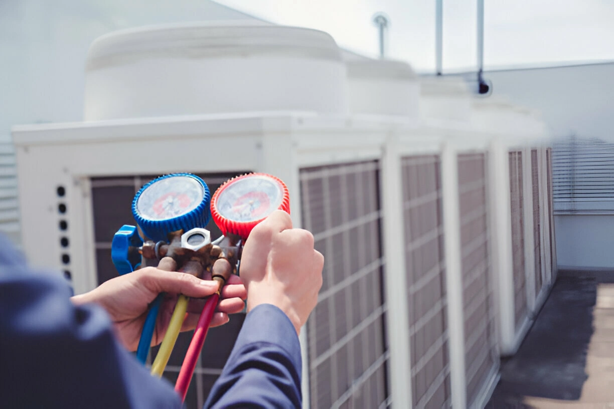 Technician performing maintenance on an outdoor AC unit condenser coil Technician performing maintenance on an outdoor AC unit condenser coil