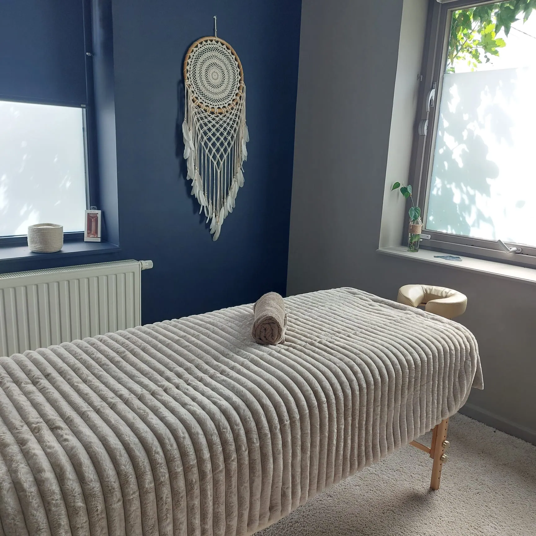 Salle de massage Shinzui près de Bruxelles avec table préparée, décoration murale bohème et lumière naturelle apaisante.