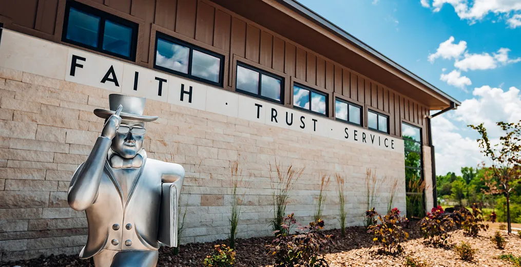 Ichabod Washburn statue in front of Jones Advisory Group's office. Office building wall says: 'FAITH · TRUST · SERVICE'.
