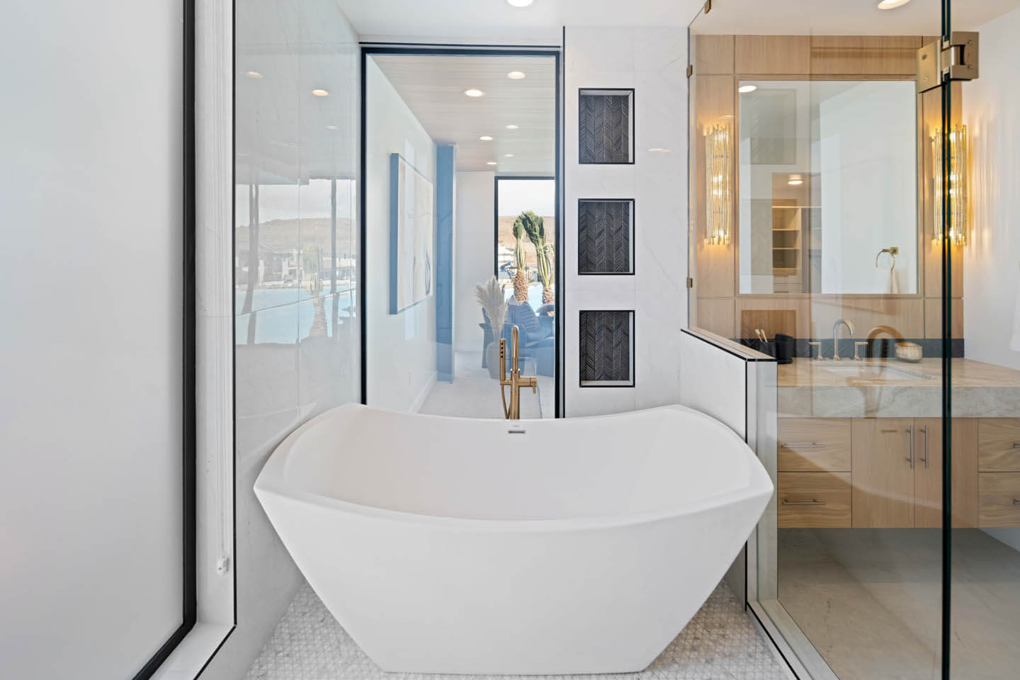 Modern white freestanding bathtub in a bright bathroom with glass shower and wooden vanity.