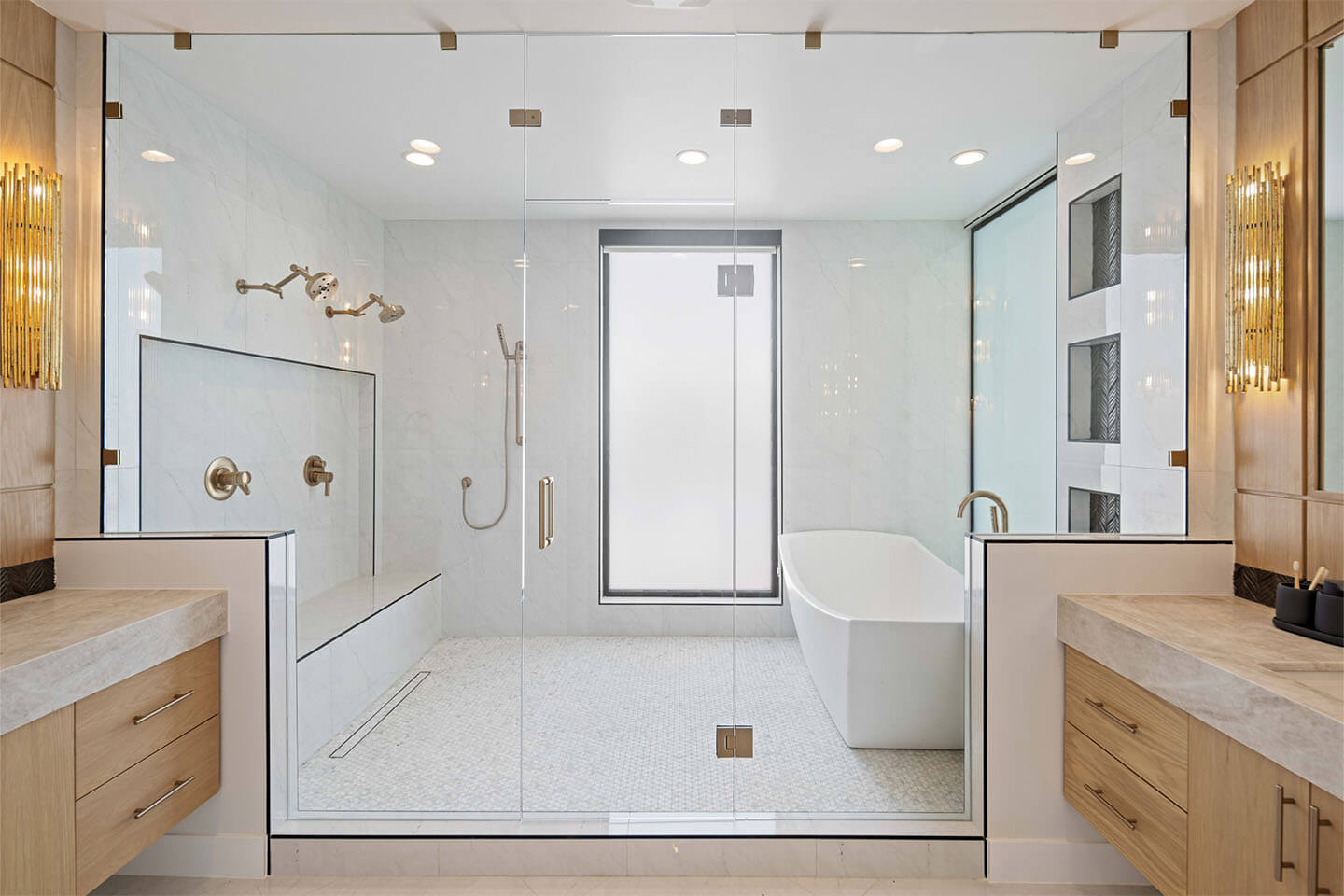 Modern bathroom with a large glass-enclosed shower featuring two showerheads and a built-in bench, a freestanding bathtub, and wooden vanities with marble countertops.