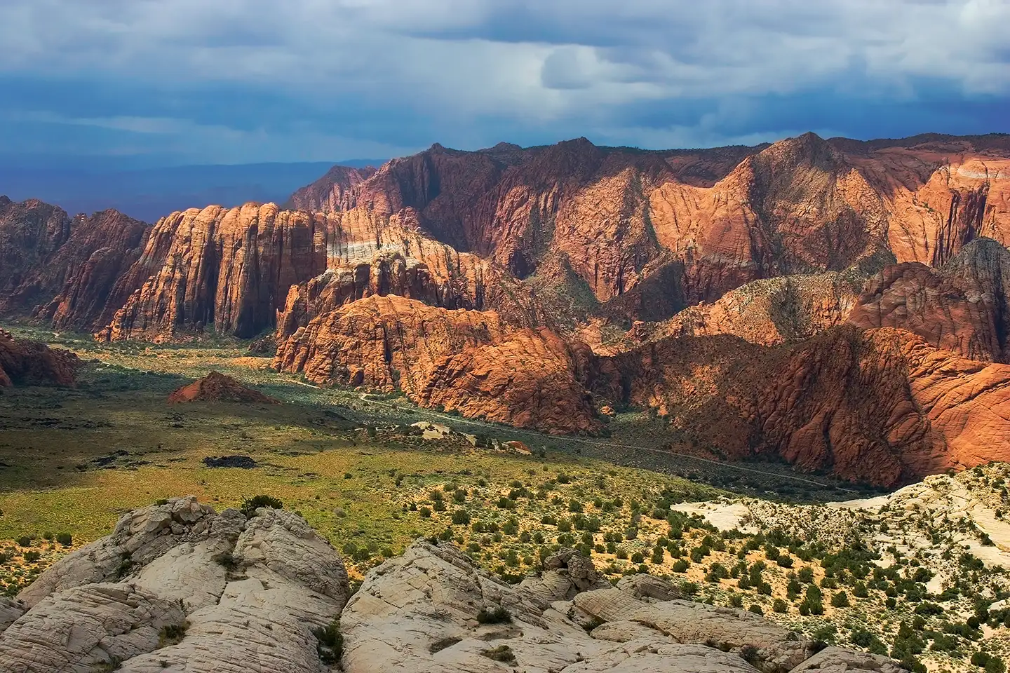 Dramatic red sandstone cliffs and valley of Snow Canyon State Park near St. George, Utah, under a stormy sky.