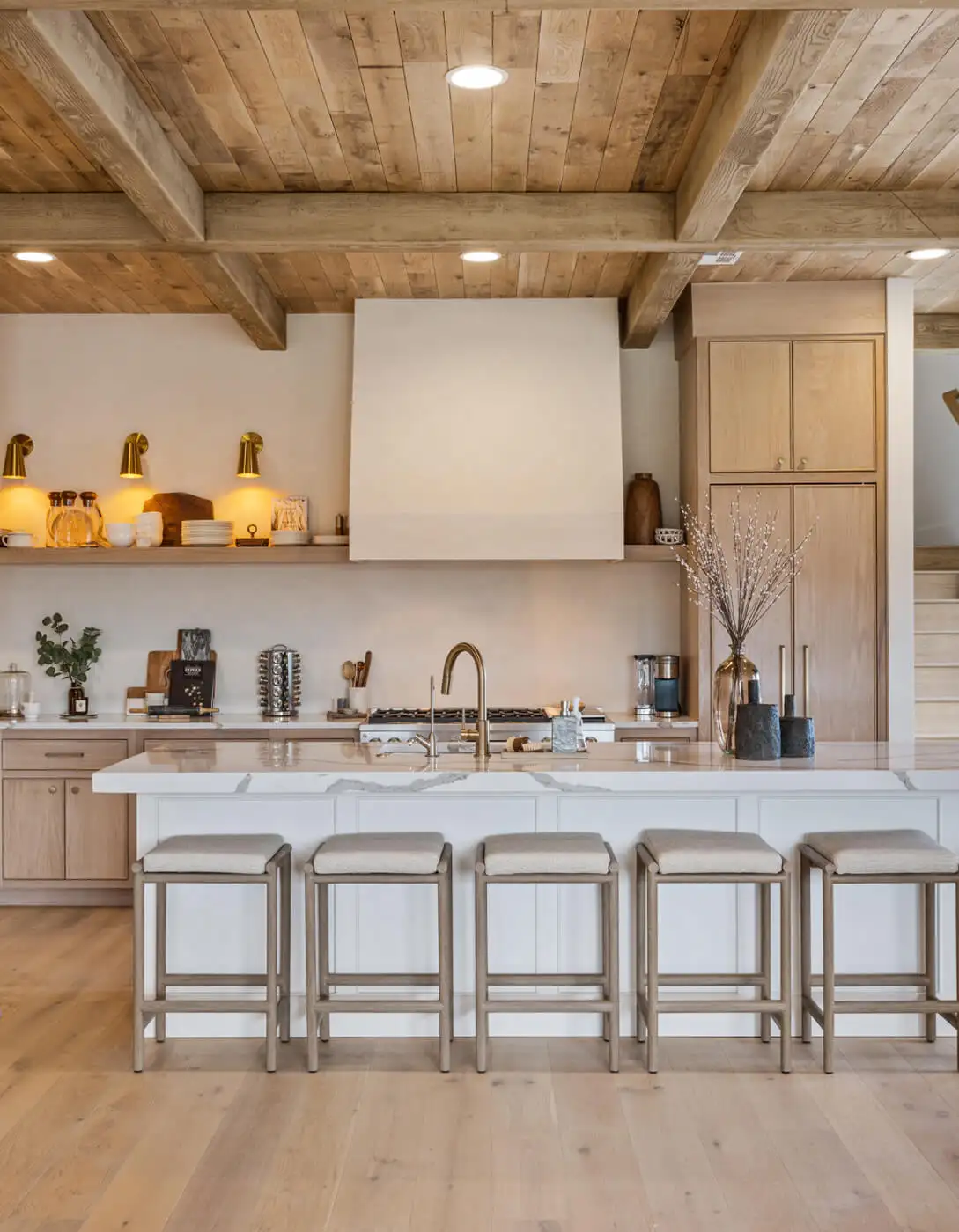 Kitchen with reclaimed wood beam ceiling, white shiplap island, light oak cabinets, and brass fixtures