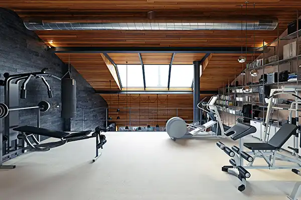 Modern loft home gym with wood ceiling, skylights, and various exercise equipment and shelving.