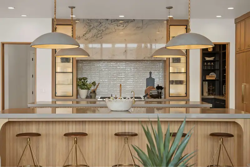 Kitchen with a wood island, leather barstools, dome pendant lights, marble backsplash, and glass-front cabinets.