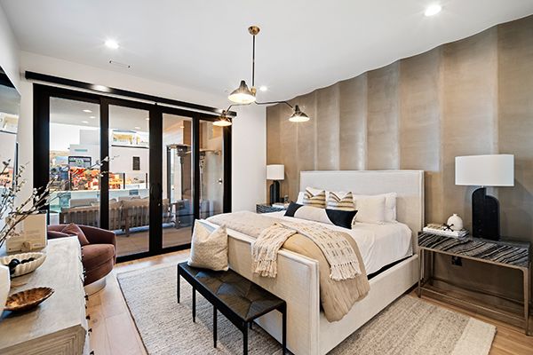 Bedroom with upholstered bed, twin lamps and nightstands, a textured accent wall, and sliding glass doors to a patio.