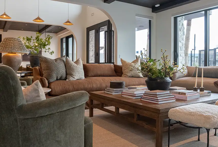 Living room with leather sofas, a wood coffee table stacked with books, and arched doorways