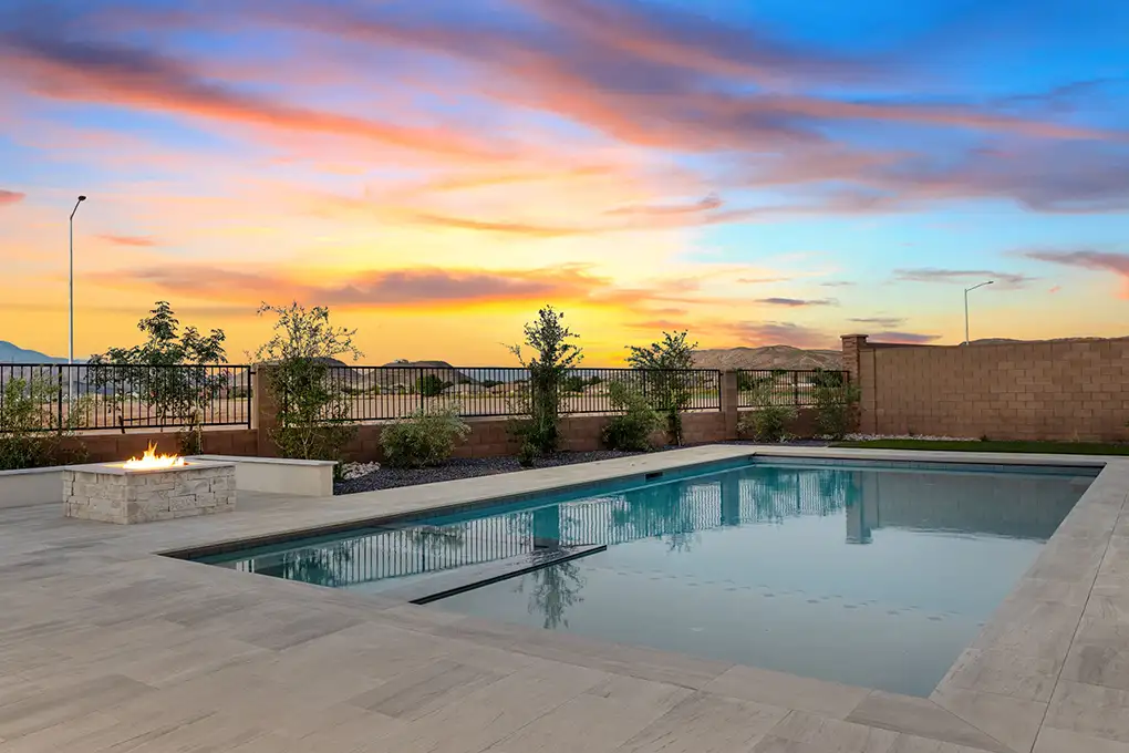 Backyard pool and fire pit under a colorful sunset sky