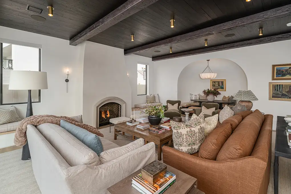 Living room with a white fireplace, dark beamed ceiling, and leather and linen sofas