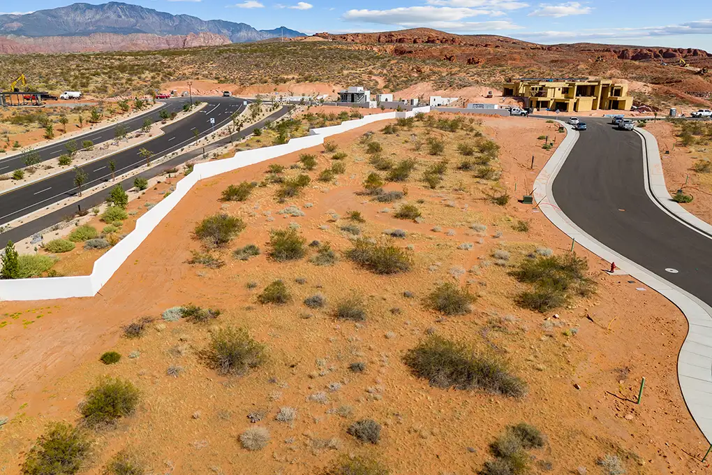 Aerial view of a desert home lot beside a curving road with red rock hills