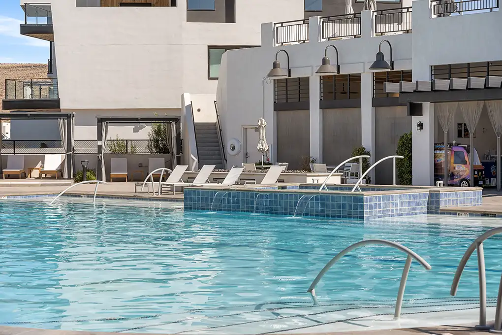 Resort-style pool with a spa and lounge chairs beside a modern building