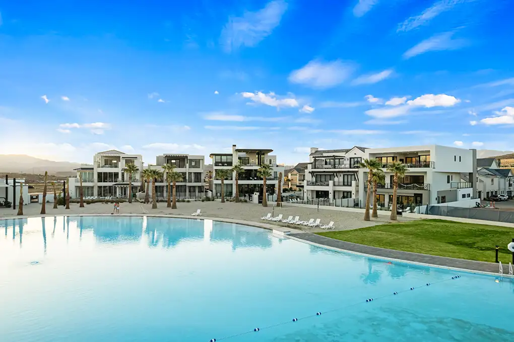 Modern homes and palm trees along a large turquoise lagoon
