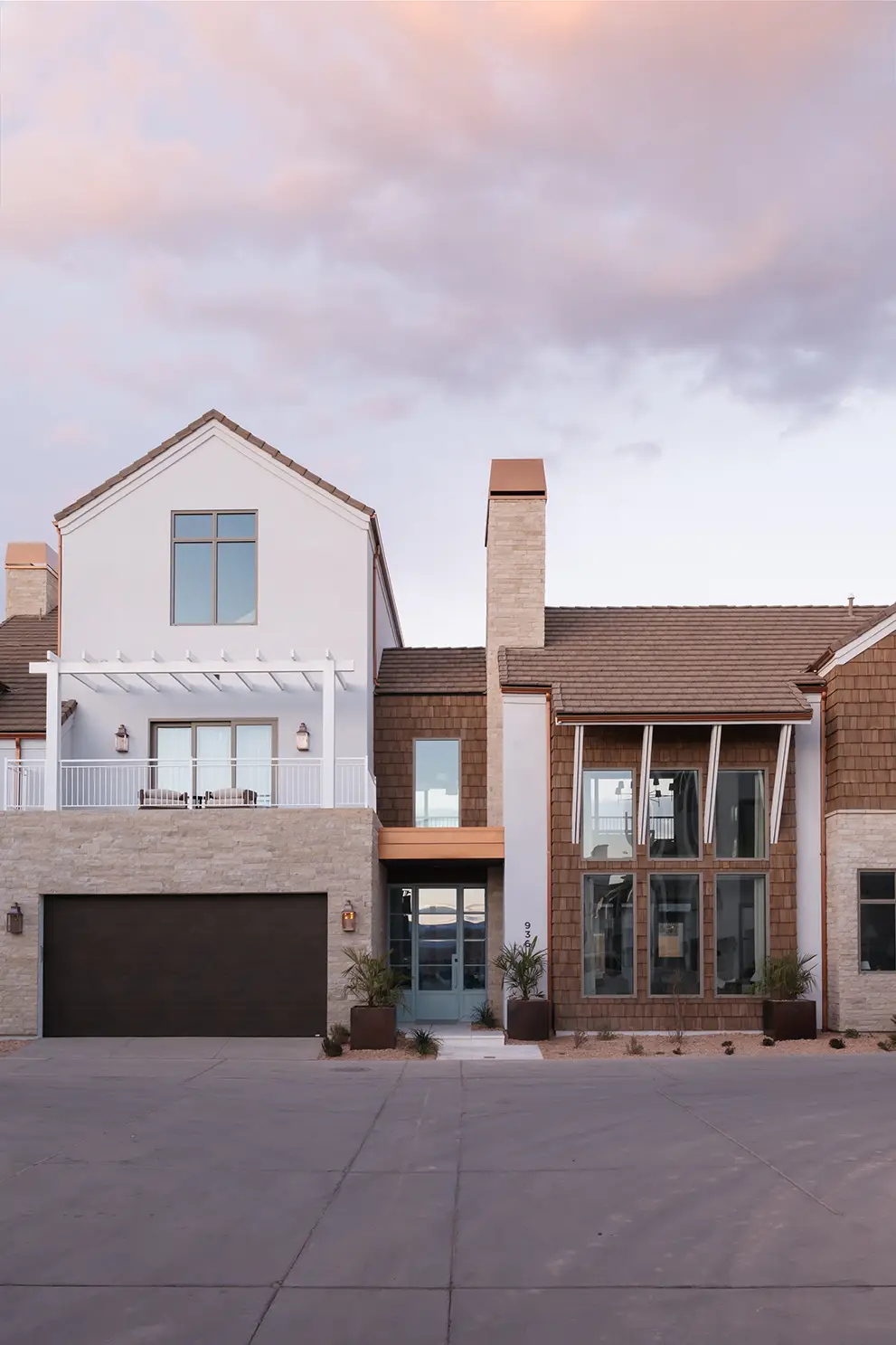 Modern luxury home exterior with stone and cedar shake siding, two-story windows, and balcony in Desert Color community, St. George, Utah