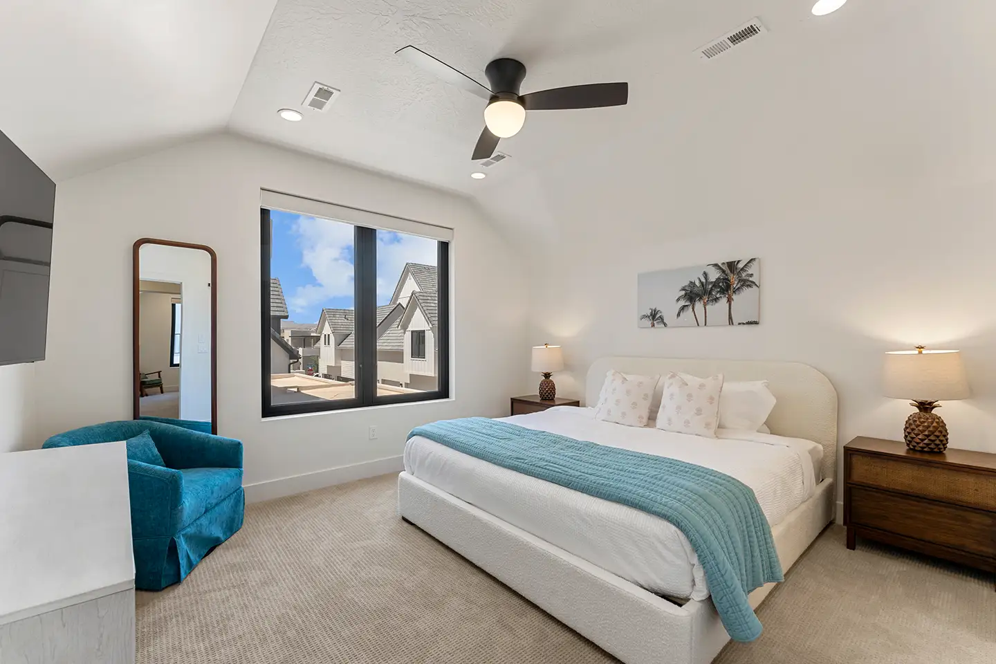 Master bedroom at Lula Cove with king bed, vaulted ceiling, teal accents, and rooftop views