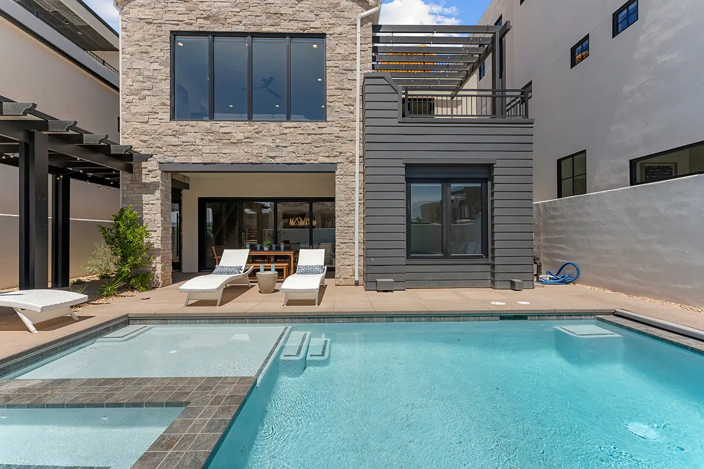 Private pool and spa at Lula Cove with lounge chairs, stone facade, and covered patio