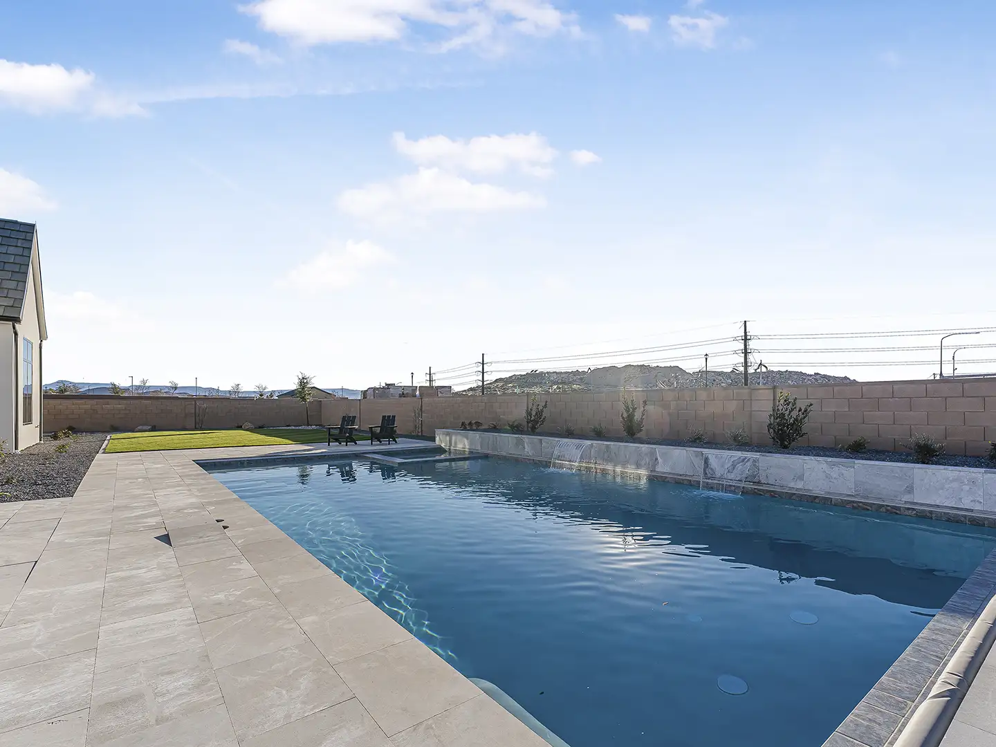 Private backyard pool with raised stone water feature, spa, paver patio, and grass lawn at a Cedar Pointe home in St. George.