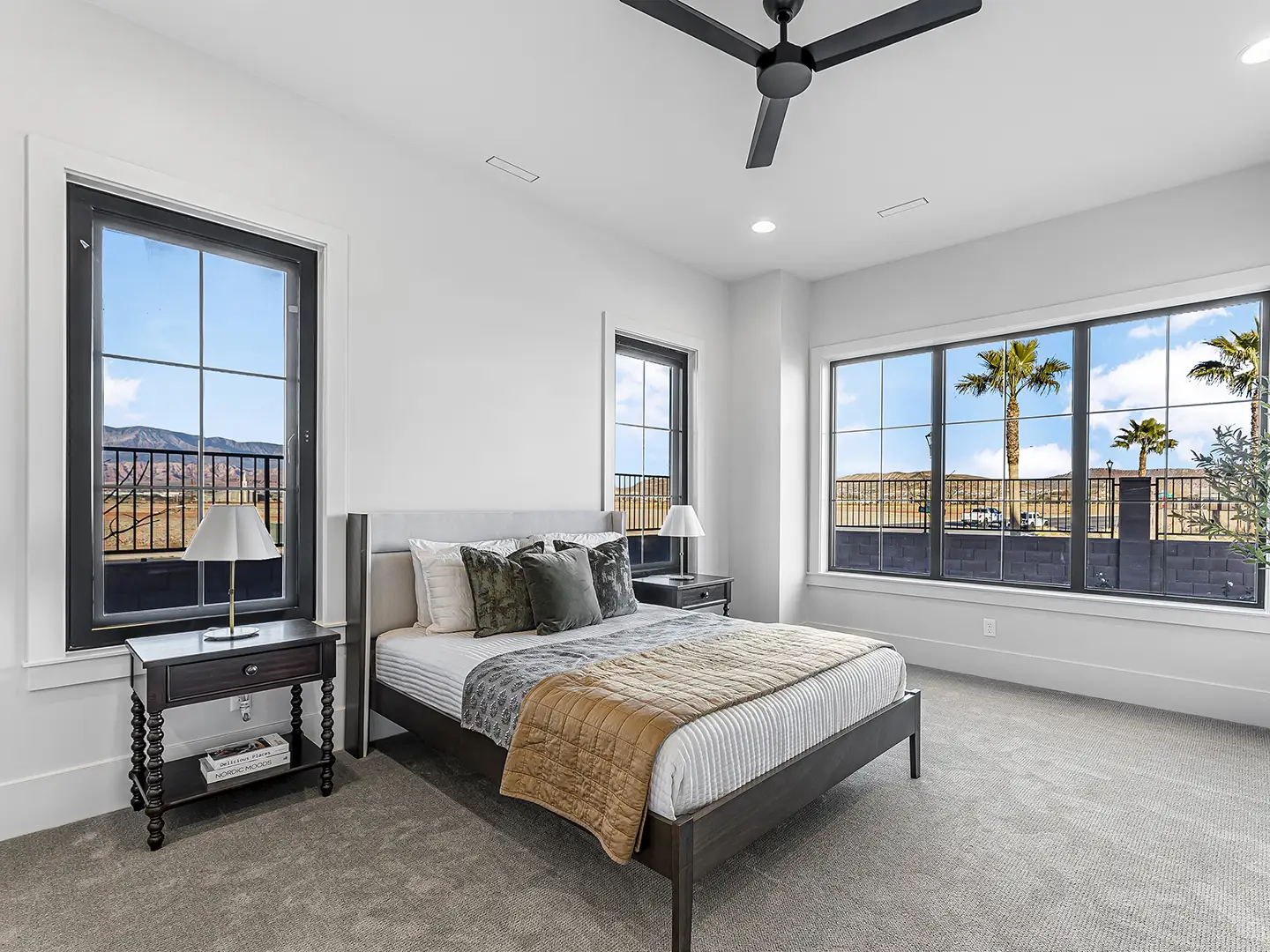 Spacious master bedroom with black-frame windows, ceiling fan, and red rock mountain views at Cedar Pointe Homes in St. George, Utah.
