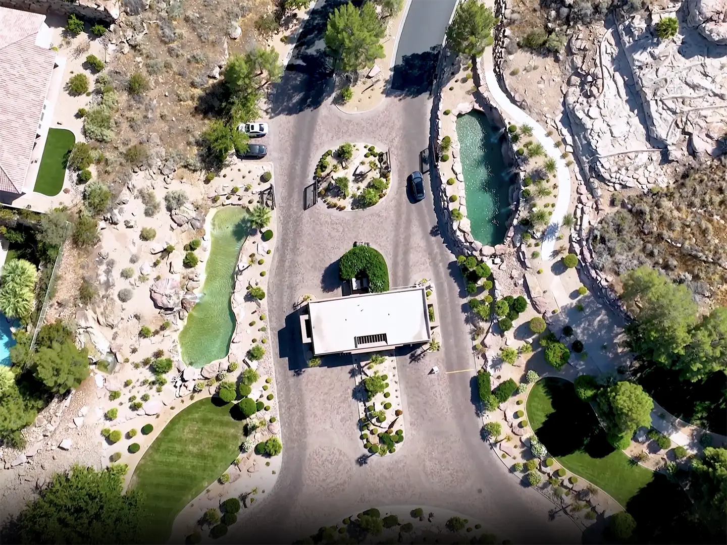 Aerial view of a luxury desert community cul-de-sac with landscaped ponds, native plants, and custom homes in southern Utah.