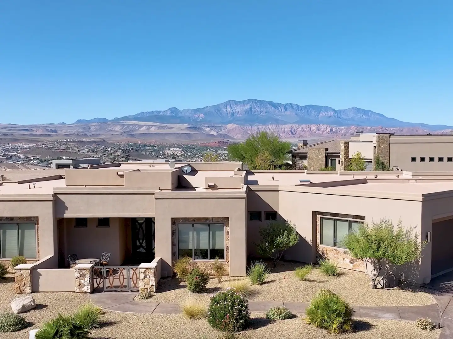 Southwest-style stucco home with stone accents and desert landscaping overlooking St. George with Pine Valley Mountains in the background.