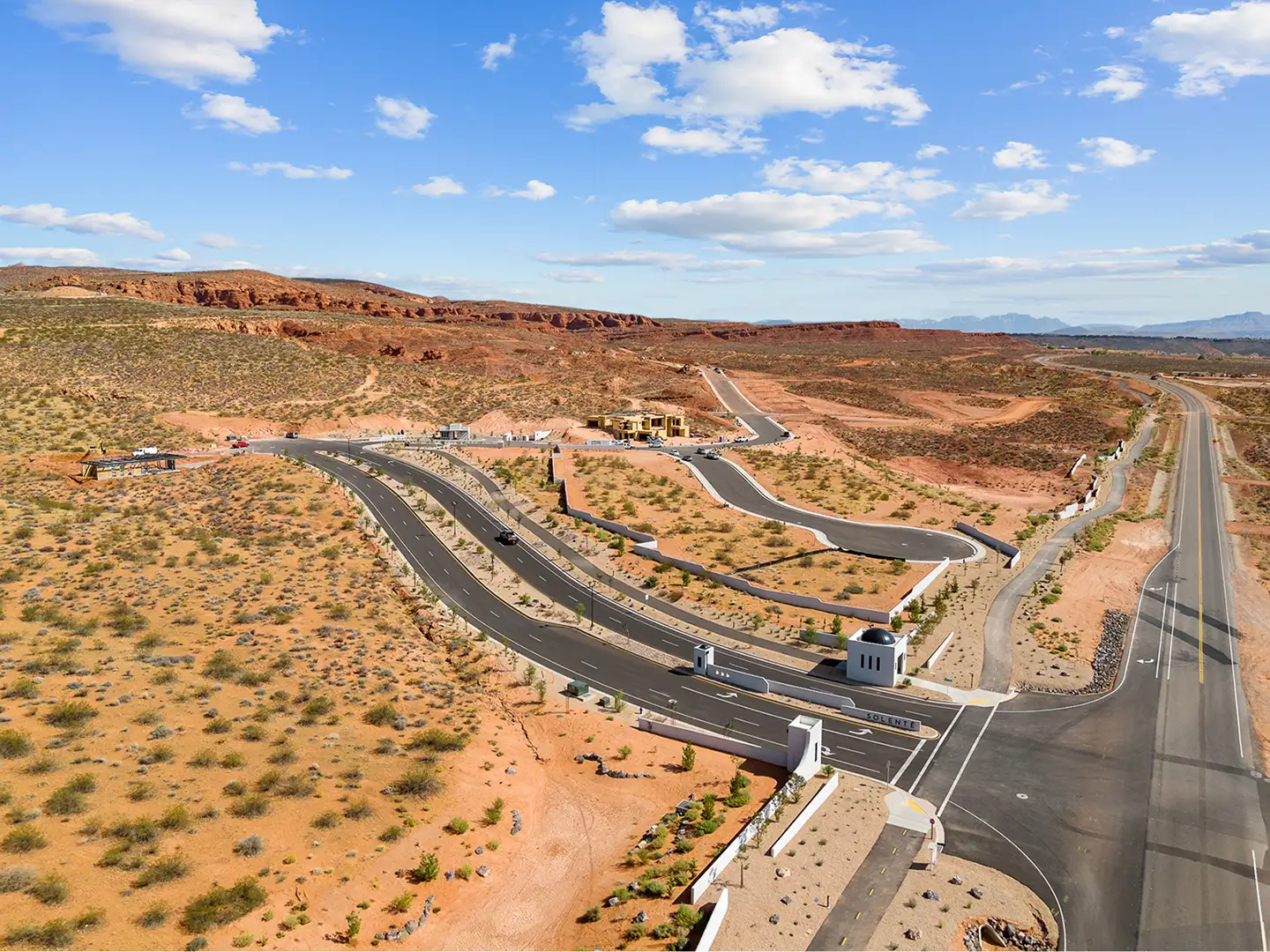 Wide aerial view of Solente community development with winding roads, gatehouse entry, and surrounding red rock desert terrain.