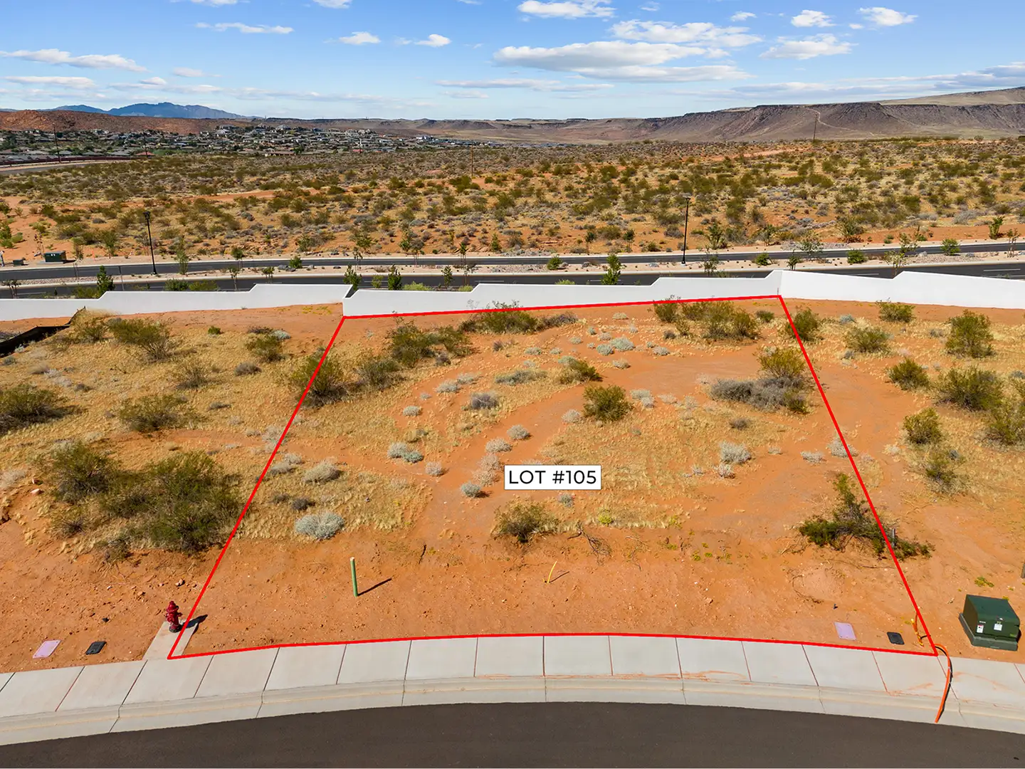 Aerial photo of Lot 105 at Solente with red boundary lines showing the vacant desert lot and surrounding community infrastructure.