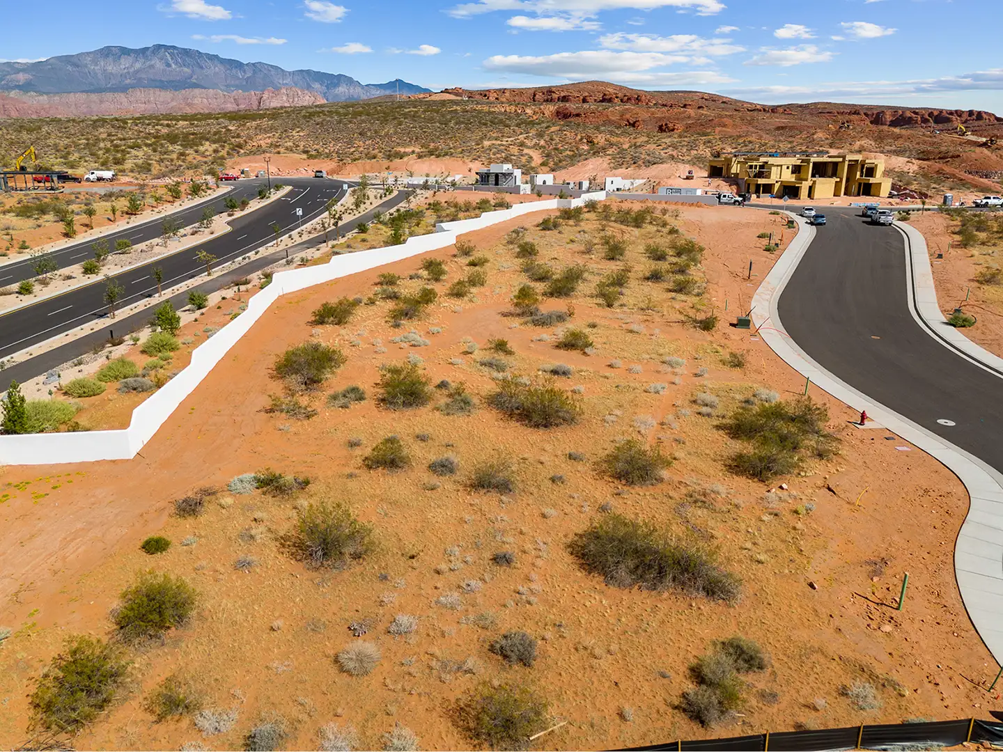 Aerial view of Solente development under construction with paved roads, home sites, and red rock cliffs in the background.
