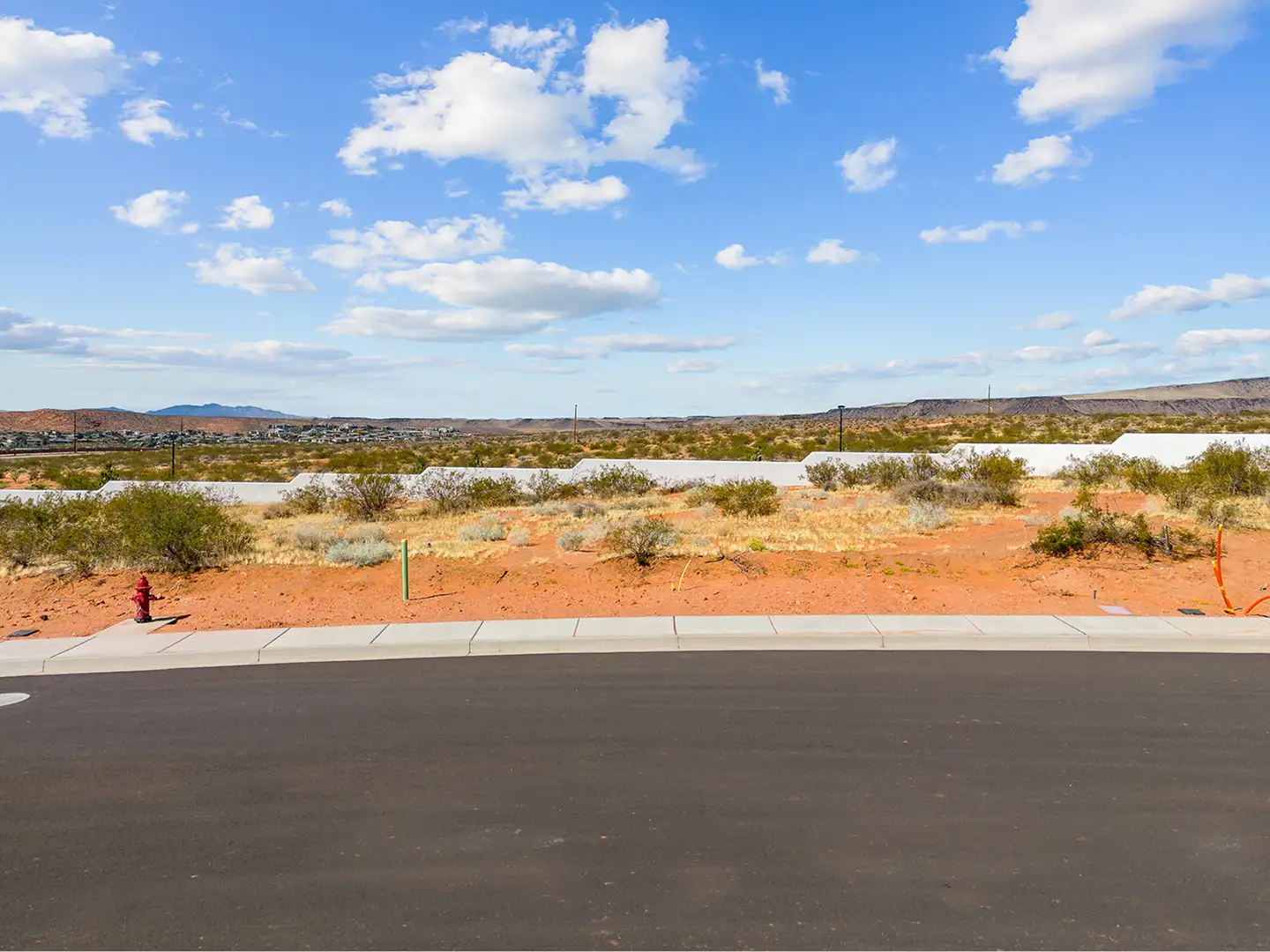 Street-level view from Lot 105 at Solente looking out over desert brush toward red rock formations and distant mountains.