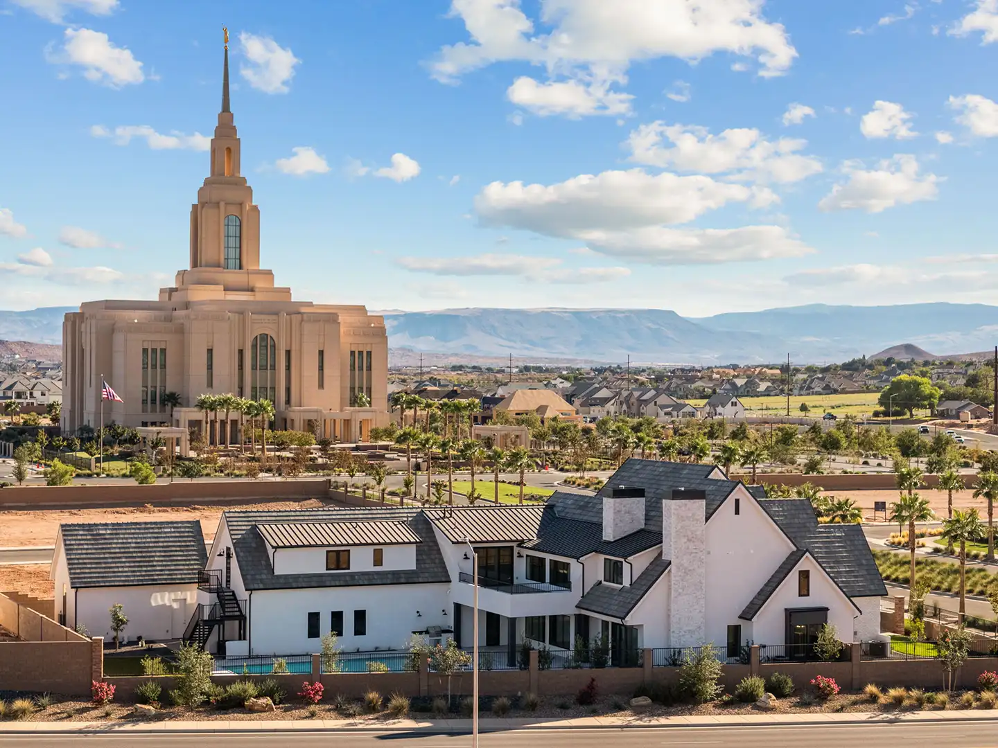 Aerial daytime view of custom homes near the temple with desert mountains in the background