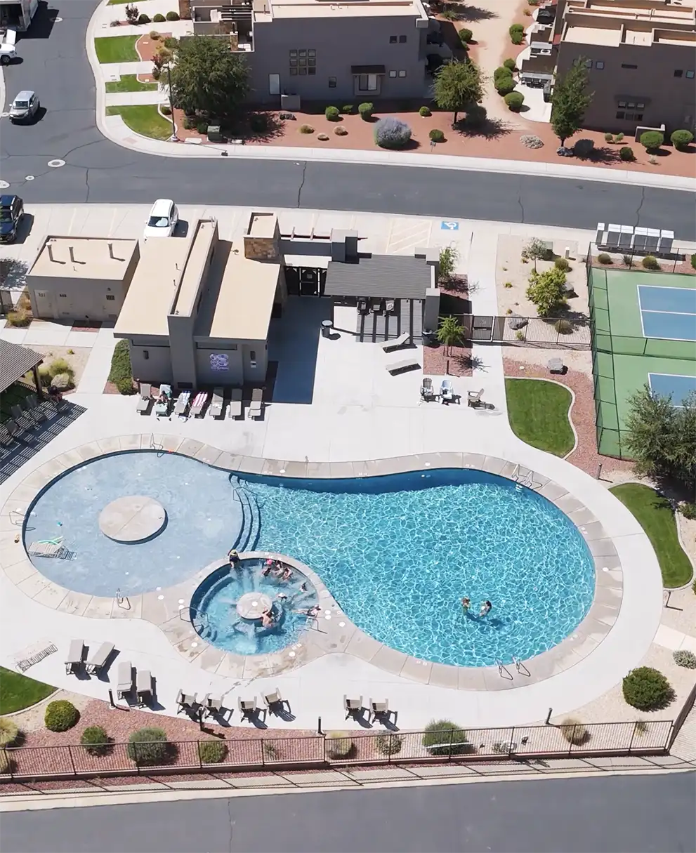 Aerial view of resort-style swimming pool, hot tub, clubhouse, and sport court at a desert community