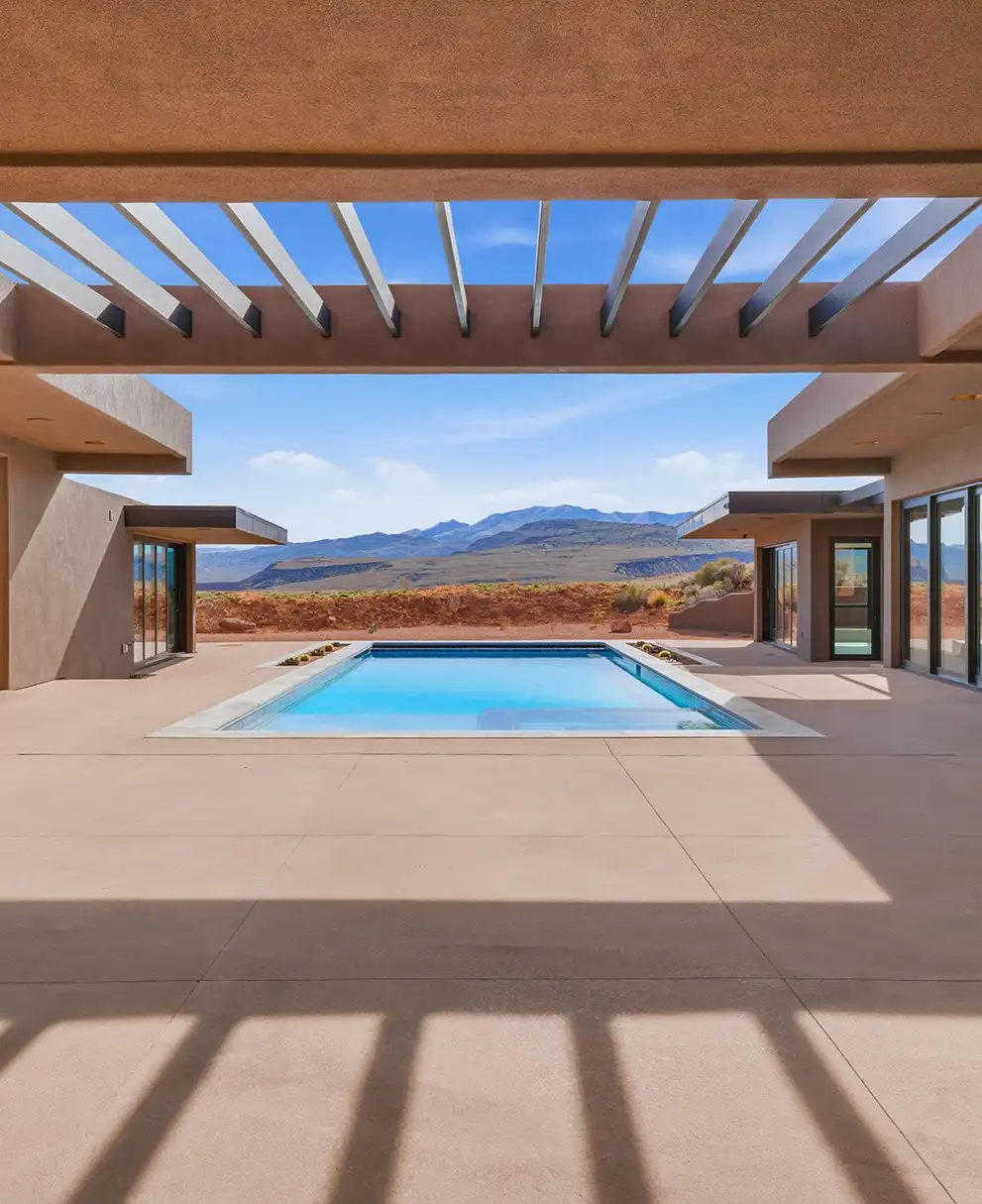 Private courtyard pool framed by modern adobe-style architecture with panoramic red rock mountain views beyond