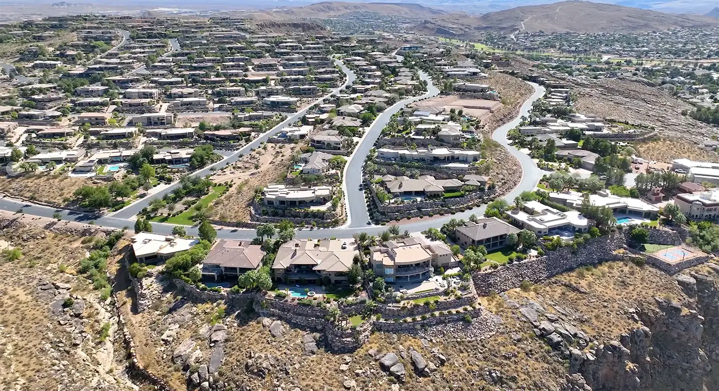 Aerial view of a hillside residential community with winding roads, luxury homes, and arid desert terrain