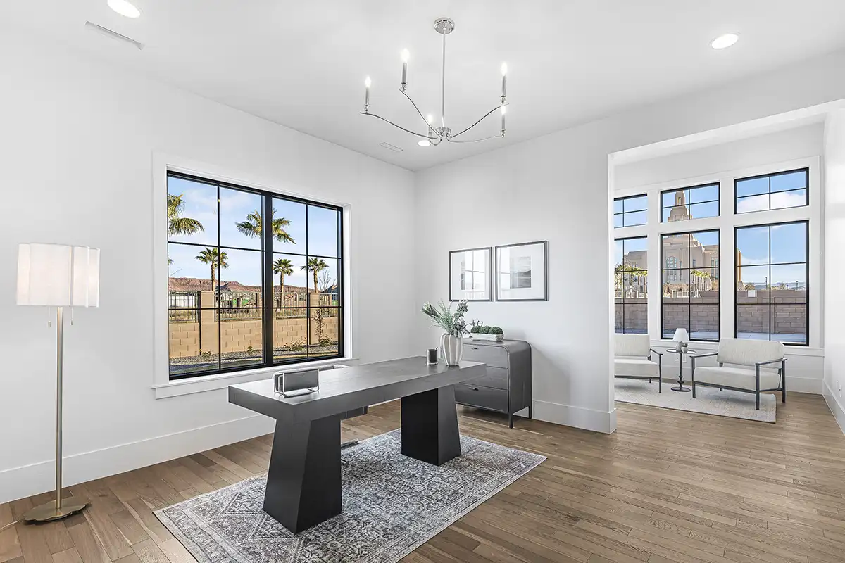 Bright contemporary home office with hardwood floors, black-frame windows, a modern desk, chandelier, and neutral minimalist decor.