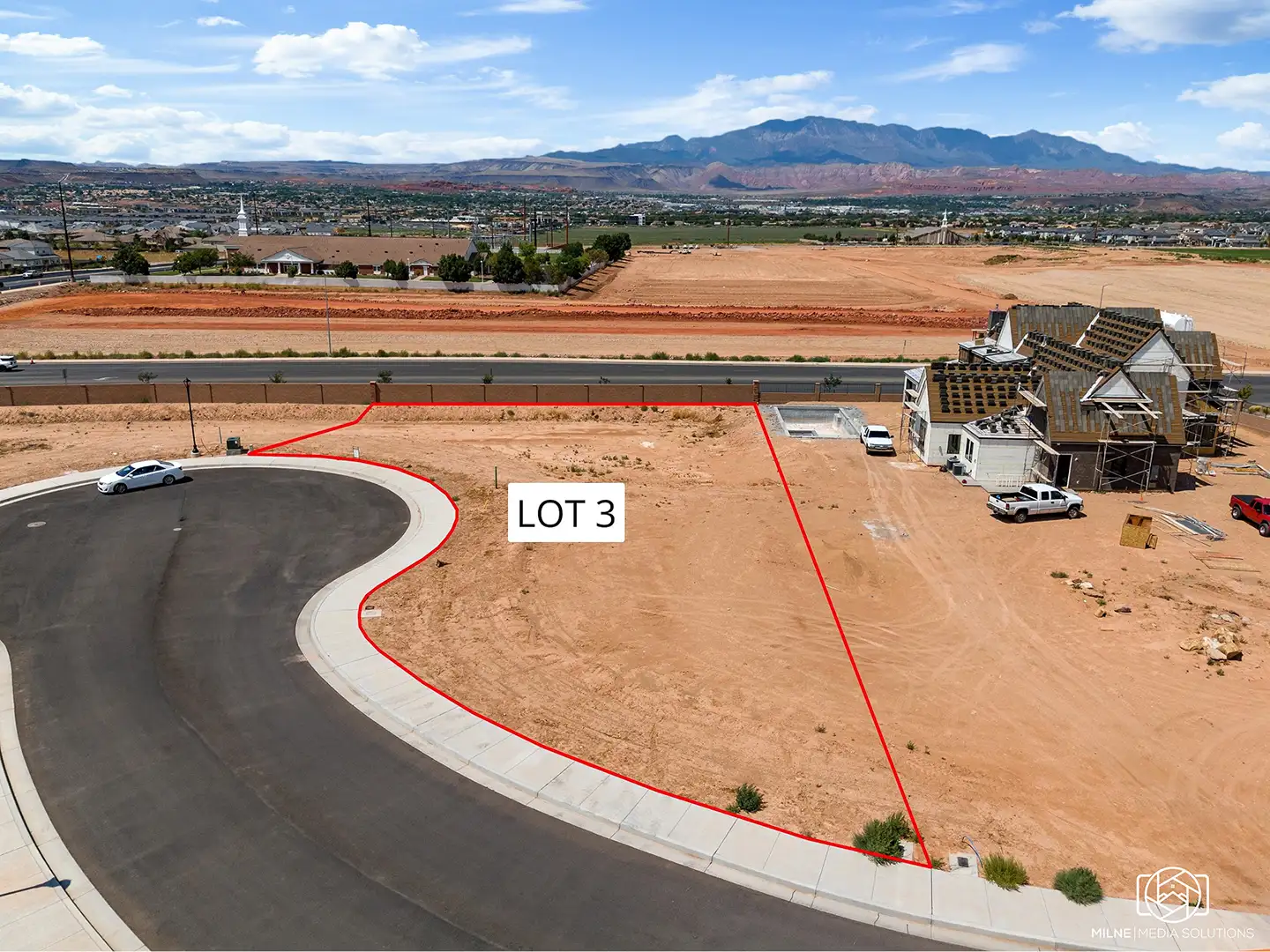 Aerial view of a home lot on a cul-de-sac facing north with mountain views, nearby construction, and open desert terrain