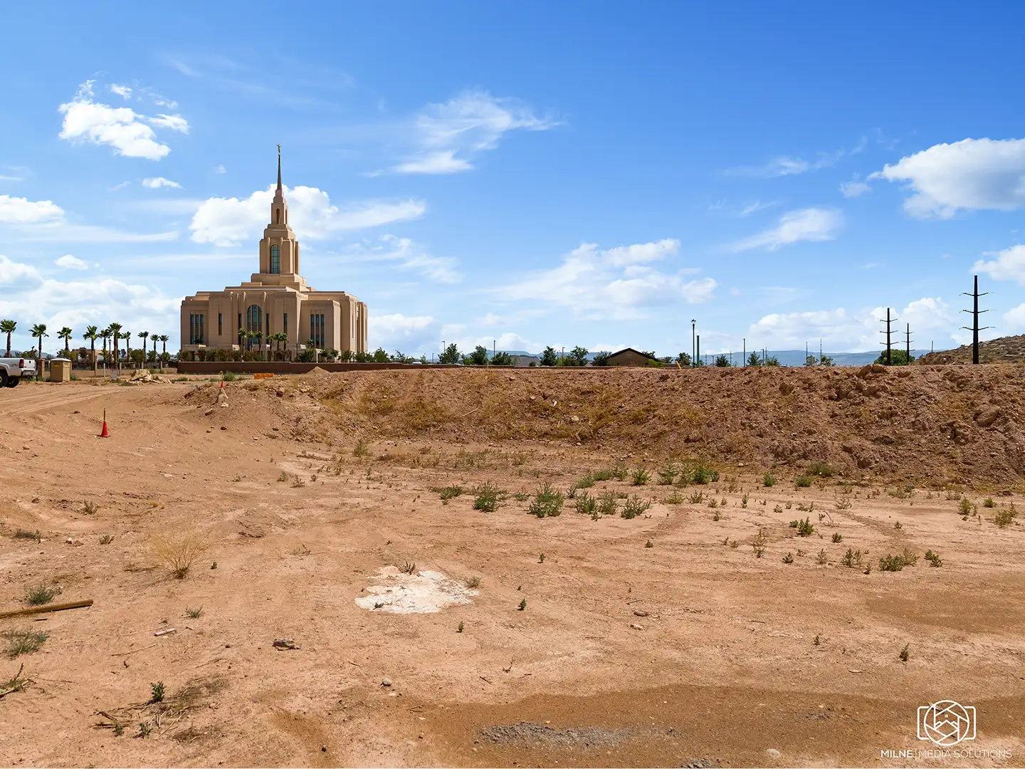 Ground-level view from a home lot looking toward a nearby temple with palm trees under a bright desert sky