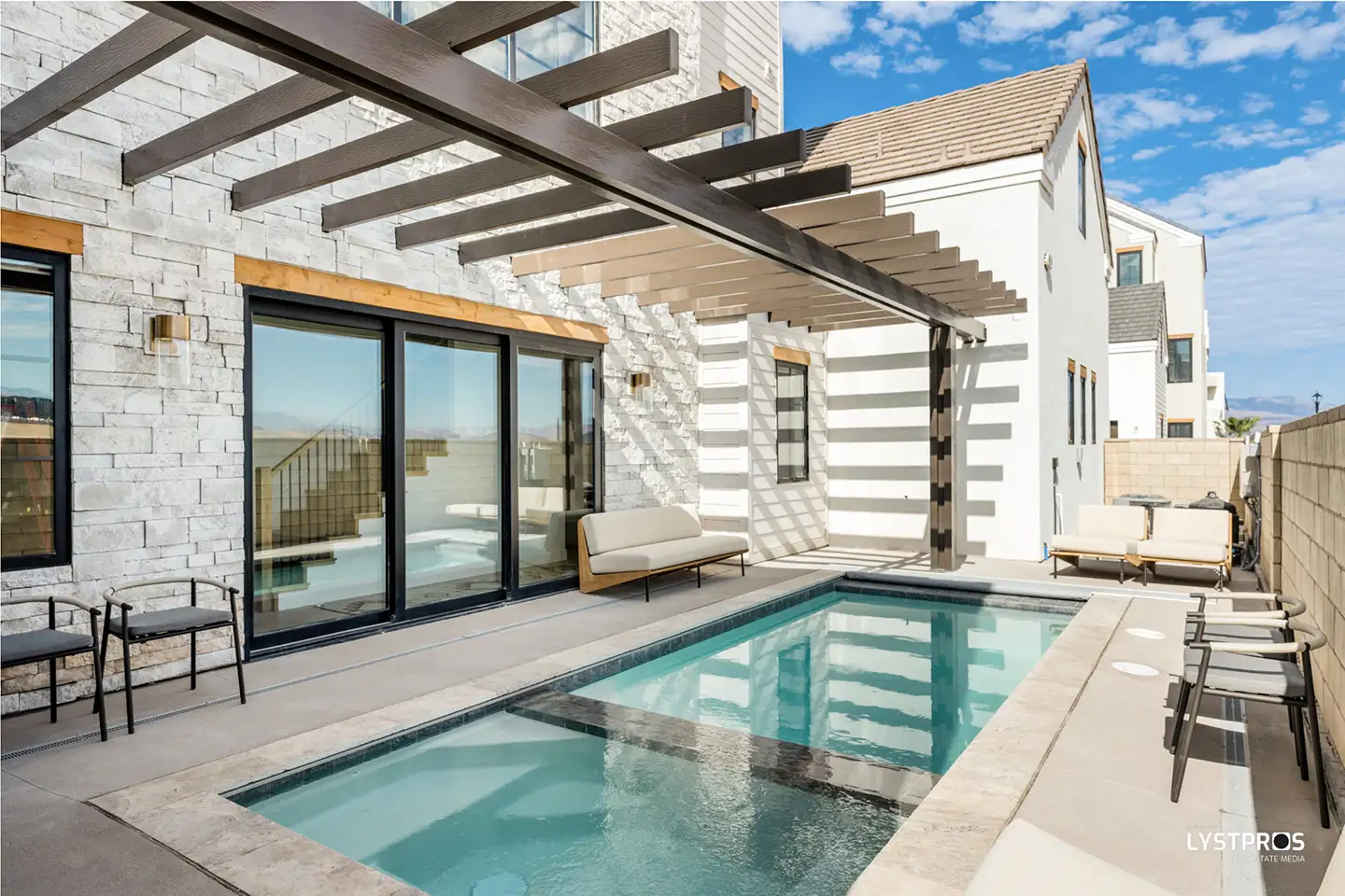 Completed move-in-ready home courtyard with private pool, pergola, stone exterior, and outdoor seating.