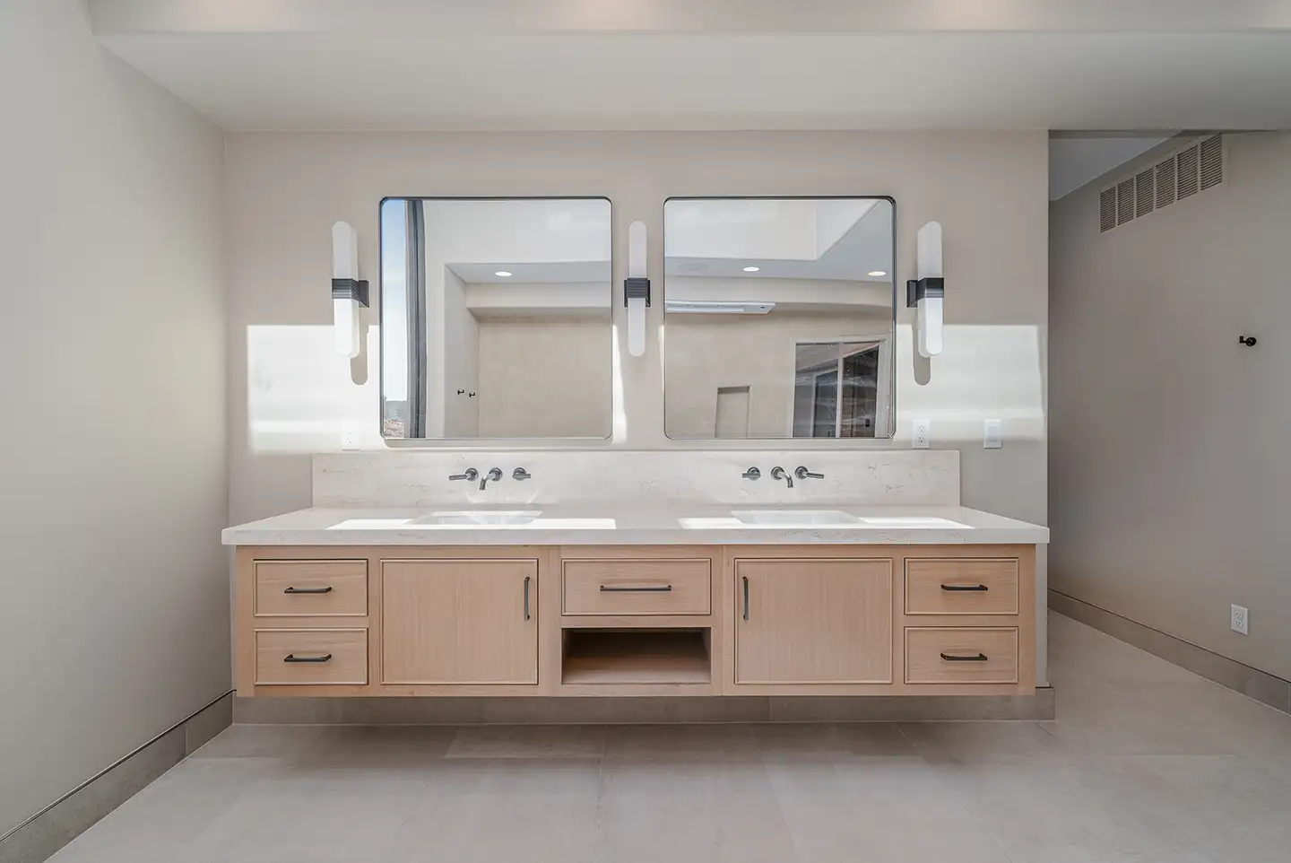 Cedar Pointe move-in-ready primary bath with floating light wood double vanity, twin mirrors, and modern sconces.