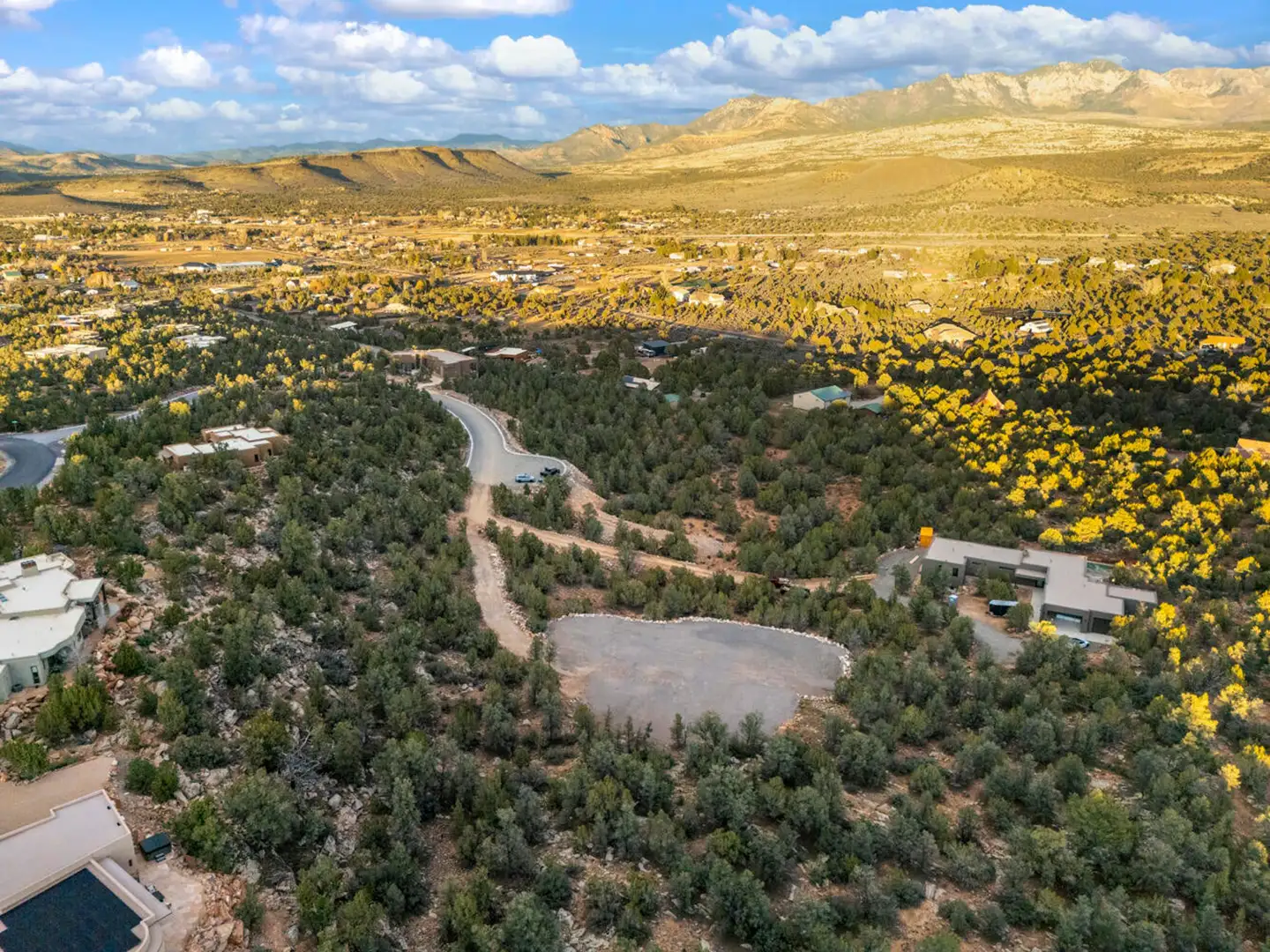 Aerial view of a homesite area with golden grasslands and layered mountain ranges stretching across the horizon.
