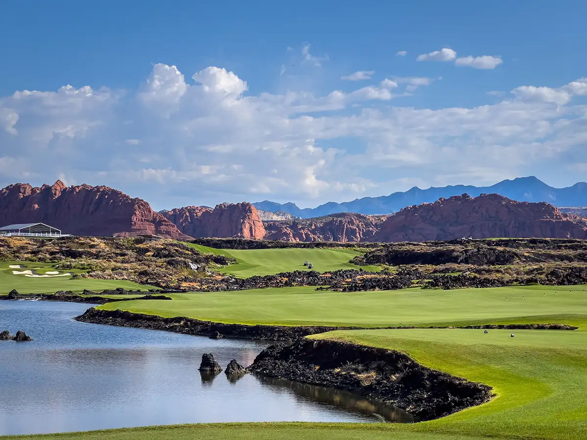 Black Desert Resort golf course with lush green fairways, black lava rock features, water hazards, and red cliff backdrop.