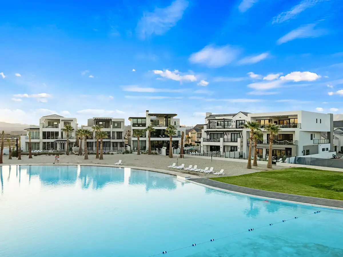 Desert Color Resort lagoon-style swimming pool surrounded by modern white luxury vacation rentals and palm trees.