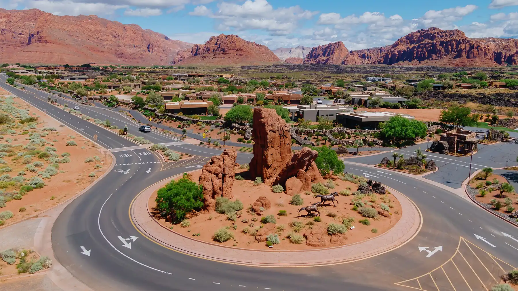A landscaped roundabout in Ivins featuring native red rock formations, with the area's red sandstone cliffs rising in the distance.