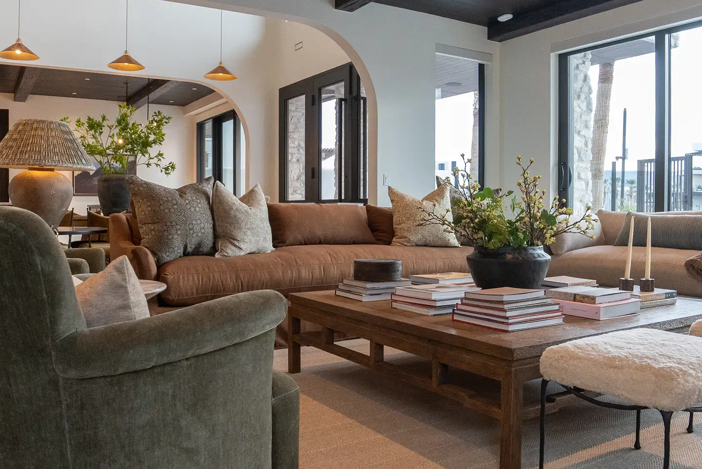 Transitional living room with a brown sectional sofa, green velvet armchair, and wood coffee table topped with stacked books.