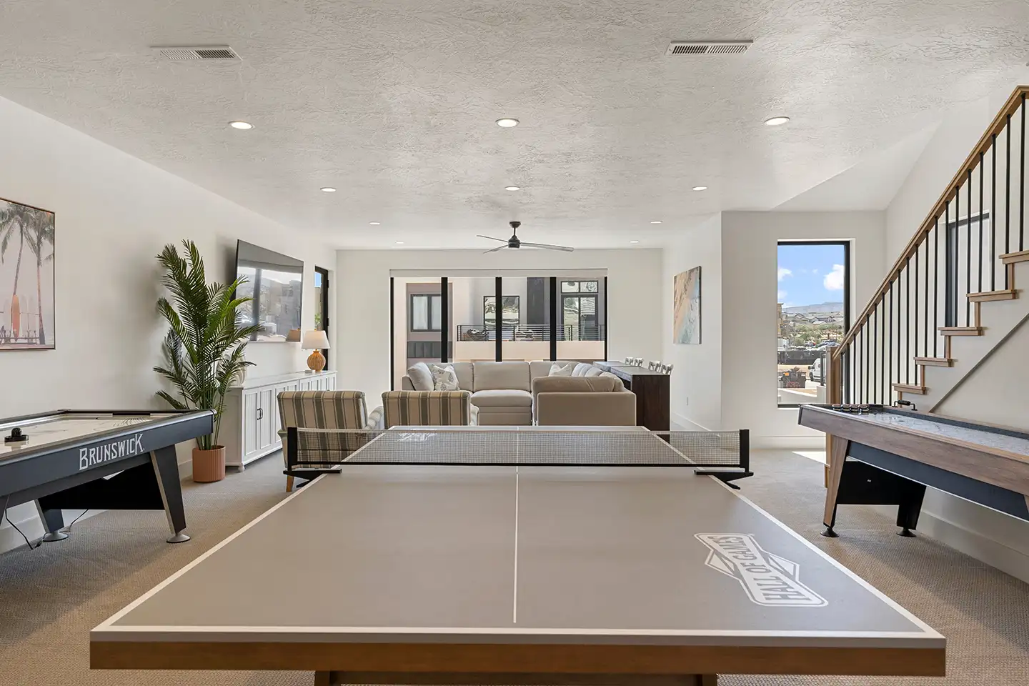 Game room with a ping pong table, air hockey, and shuffleboard near a lounge seating area.