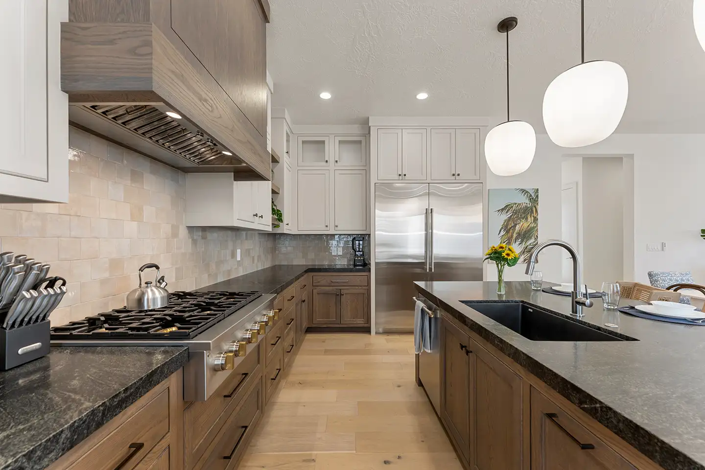 Luxury kitchen with wood cabinets, a gas range, dark stone countertops, and a large island.