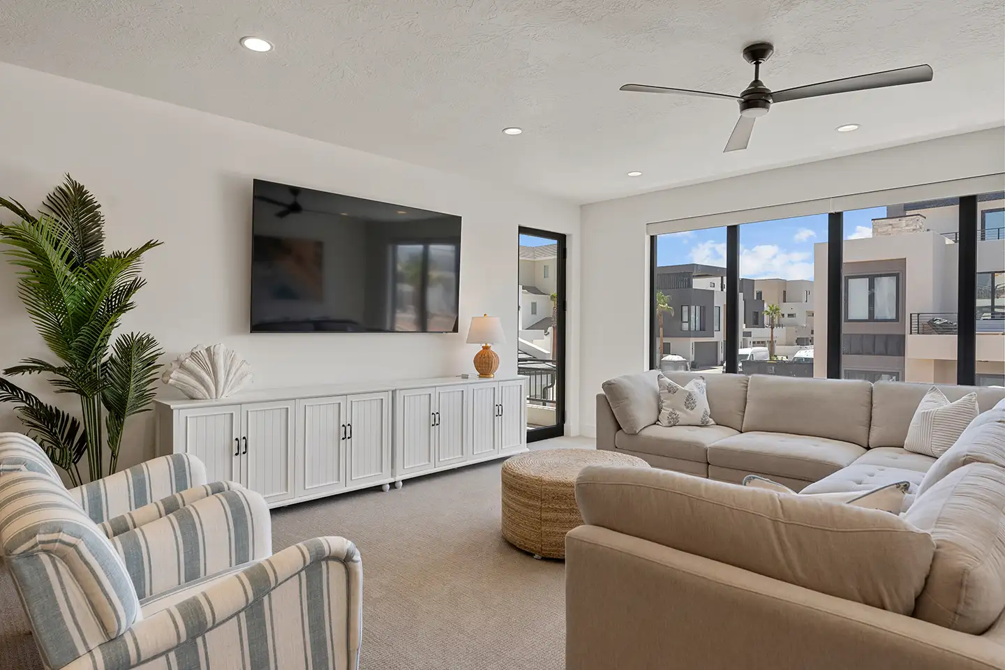 Upstairs living loft with a sectional sofa, TV, and large windows overlooking the neighborhood.
